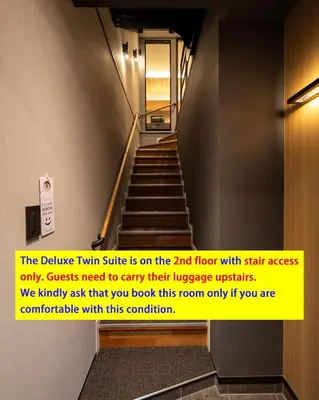 a hallway with stairs with a yellow sign on it at Tokyo Modern Stay Shinjuku in Tokyo