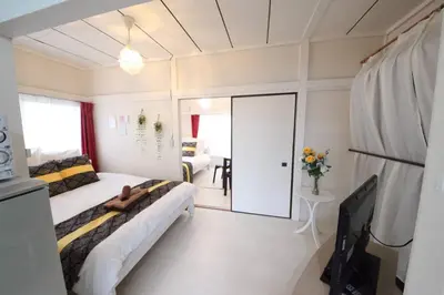 a bedroom with two beds and a room with a table at Okubo Daiichi House2C OD2C in Tokyo