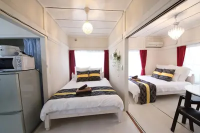 two beds in a small room with red curtains at Okubo Daiichi House2C OD2C in Tokyo