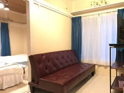 a brown couch in a room with a bed at Okubo Daiichi House 1B OD1B in Tokyo