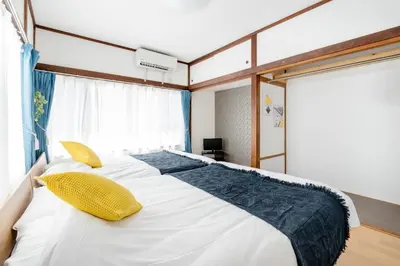 a bedroom with a large white bed with yellow pillows at Chelsea Hatsudai 201 CH21 in Tokyo