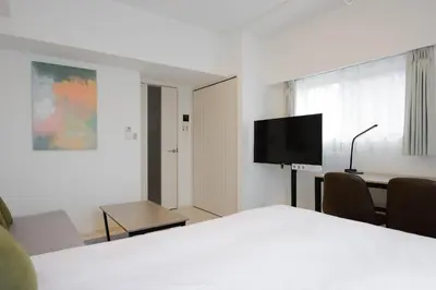 a room with a bed and a desk and a tv at Noble Park RYOGOKU in Tokyo