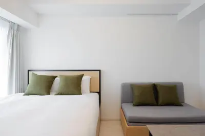 a bedroom with a bed and a couch next to a window at Noble Park RYOGOKU in Tokyo