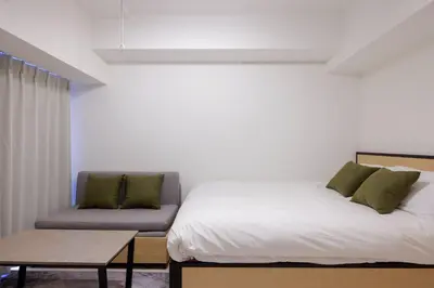 a bed and a couch in a room at Noble Park RYOGOKU in Tokyo