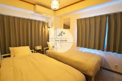 two beds in a room with a sign that reads tar magic at ZenAbode303 \u7fbd\u7530\u7a7a\u6e2f\u96fb\u8eca8\u5206 \u90fd\u5fc3\u30a8\u30ea\u30a2\u96fb\u8eca12\u5206 in Tokyo