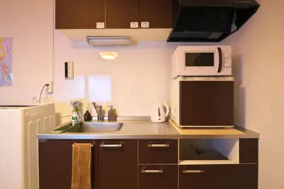 a small kitchen with a sink and a microwave at ZenAbode303 \u7fbd\u7530\u7a7a\u6e2f\u96fb\u8eca8\u5206 \u90fd\u5fc3\u30a8\u30ea\u30a2\u96fb\u8eca12\u5206 in Tokyo