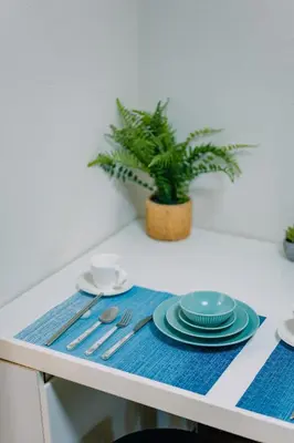 a table with a blue place mat with plates and a plant at Natsumi 2 \u30db\u30c6\u30eb in Tokyo