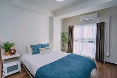 a bedroom with a bed with a blue blanket and a window at Natsumi 2 \u30db\u30c6\u30eb in Tokyo