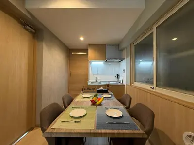 a dining room with a table and chairs and a kitchen at nestay inn tokyo tsukiji in Tokyo