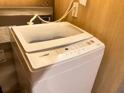 a white washing machine sitting in a room at nestay inn tokyo tsukiji in Tokyo