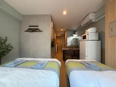 two beds in a small room with a kitchen at nestay inn tokyo tsukiji in Tokyo