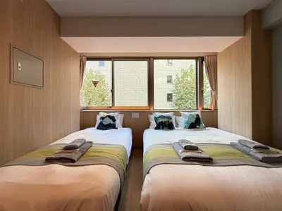 two beds in a room with a window at nestay inn tokyo tsukiji in Tokyo