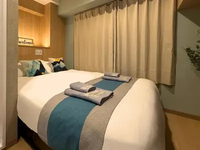 a bedroom with a large bed with two towels on it at nestay inn tokyo tsukiji in Tokyo