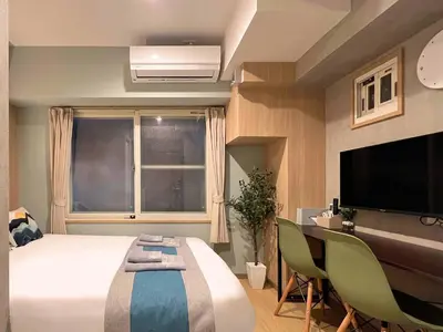 a bedroom with a bed and a desk and a television at nestay inn tokyo tsukiji in Tokyo