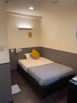 a bedroom with a bed with a yellow pillow on it at Hotel Grand Fort - Vacation STAY 85455v in Tokyo