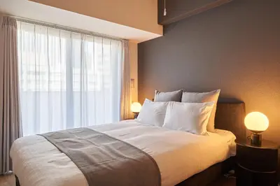 a bedroom with a bed with two lamps and a window at \u30a2\u30eb\u30c8\u30f4\u30a3\u30e9\u864e\u30ce\u9580 in Tokyo