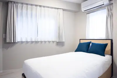 a bedroom with a bed with blue pillows and a window at PREAs\u4e2d\u91ce\u65b0\u4e95 in Tokyo