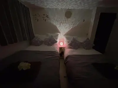 two beds in a room with a light on the wall at Spacious Cozy house in Shinjuku Free parking wifi in Tokyo