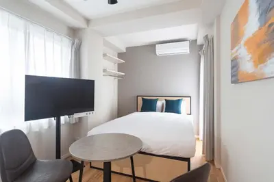 a bedroom with a bed and a table and a tv at Jeunesse\u7acb\u82b1 in Tokyo