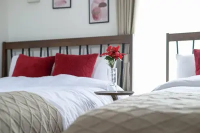 a bedroom with two beds and a vase with a red flower at Origami-ya Stay Zen - Luxury Asakusa Penthouse in Tokyo