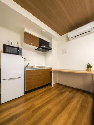 a kitchen with a white refrigerator and wooden floors at japan house Ikebukuro 2 in Tokyo