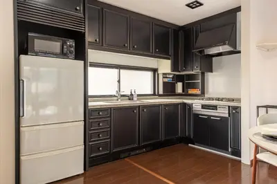 a kitchen with black cabinets and a white refrigerator at \u8aa0\u5fc3\u58024f in Tokyo