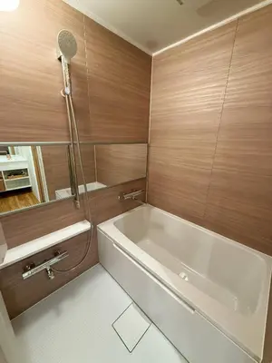 a bathroom with a white tub and wooden walls at Etsu in Tokyo