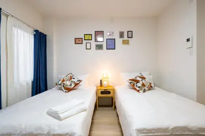 two beds in a room with a table and a window at Home Story in Tokyo \u6c5f\u6238\u5ddd\u533a\u5e73\u4e95\u99c5-\u4e0a\u91ce \u79cb\u8449\u539f\u307e\u3067\u76f4\u901a in Tokyo