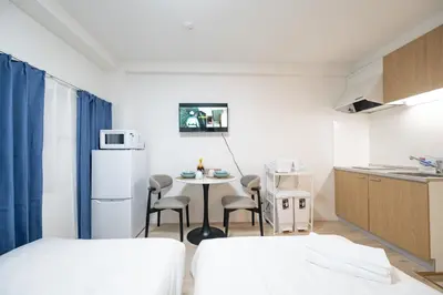 a small room with a kitchen and a table with chairs at Home Story in Tokyo \u6c5f\u6238\u5ddd\u533a\u5e73\u4e95\u99c5-\u4e0a\u91ce \u79cb\u8449\u539f\u307e\u3067\u76f4\u901a in Tokyo