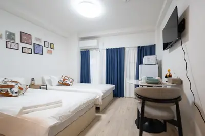 a bedroom with two beds and a table and a chair at Home Story in Tokyo \u6c5f\u6238\u5ddd\u533a\u5e73\u4e95\u99c5-\u4e0a\u91ce \u79cb\u8449\u539f\u307e\u3067\u76f4\u901a in Tokyo