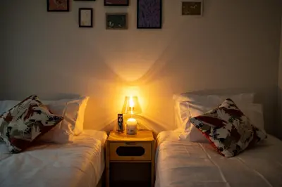 two beds in a room with a lamp on a night stand at Home Story in Tokyo \u6c5f\u6238\u5ddd\u533a\u5e73\u4e95\u99c5-\u4e0a\u91ce \u79cb\u8449\u539f\u307e\u3067\u76f4\u901a in Tokyo
