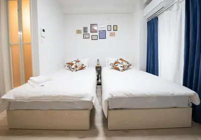 two beds sitting next to each other in a room at Home Story in Tokyo \u6c5f\u6238\u5ddd\u533a\u5e73\u4e95\u99c5-\u4e0a\u91ce \u79cb\u8449\u539f\u307e\u3067\u76f4\u901a in Tokyo