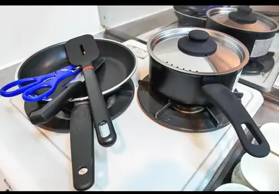 a pot on a stove with a pair of scissors at Shirokane Apartment Hotel 3 in Tokyo