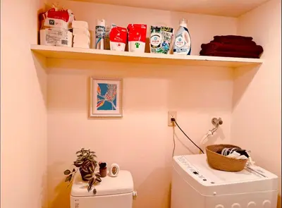 a laundry room with a shelf above a washing machine at Shirokane Apartment Hotel 3 in Tokyo