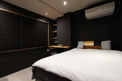 a bedroom with a white bed and a black wall at Real Life IIDABASHI in Tokyo