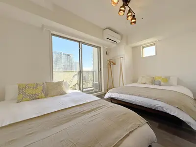 two beds in a room with a large window at The Plars in Tokyo