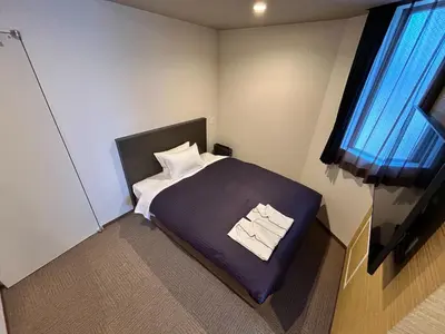 a small bedroom with a bed and a window at HOTEL LiVEMAX Mita Ekimae in Tokyo