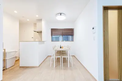 a white kitchen with a table and chairs at Manere in Tokyo