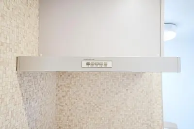a clock in a bathroom with a tiled wall at Manere in Tokyo