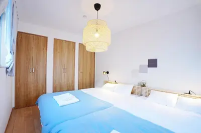 a bedroom with a large blue bed with a chandelier at Manere in Tokyo