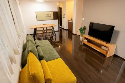 a living room with a green couch with yellow pillows at Hotel Yuga - Vacation STAY 82984v in Tokyo