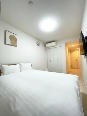 a bedroom with a large white bed and a light at japan house Otsuka in Tokyo