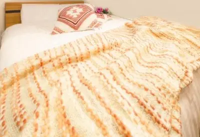 a bed with an orange and white blanket on it at japan house Otsuka in Tokyo