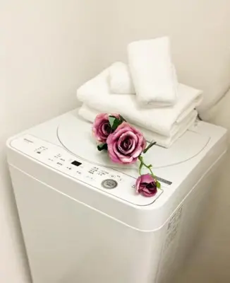 a pile of towels and flowers on top of a washing machine at japan house Otsuka in Tokyo