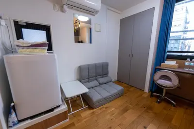 a living room with a gray couch and a mirror at YIYou Japan\u79cb\u8449\u539f302 in Tokyo