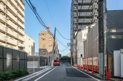 a red truck driving down a street between tall buildings at Fuukanto Kinshicho BNB in Tokyo