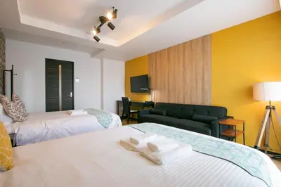 a hotel room with two beds and a chair at Randor Residence Tokyo Annex in Tokyo