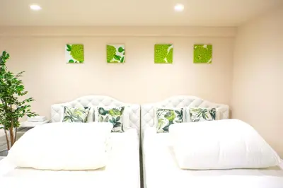 two white beds in a bedroom with green art on the wall at Avinity Higashi Nakano 1F - Vacation STAY 87308v in Tokyo