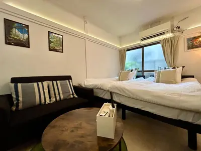 a room with two beds and a couch and a table at Cozy Residential Retreat! Easy Access to Ikebukuro & Shinjuku in Tokyo