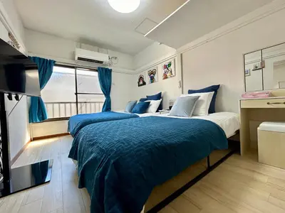 two beds in a room with blue comforter at Cozy Residential Retreat! Easy Access to Ikebukuro & Shinjuku in Tokyo